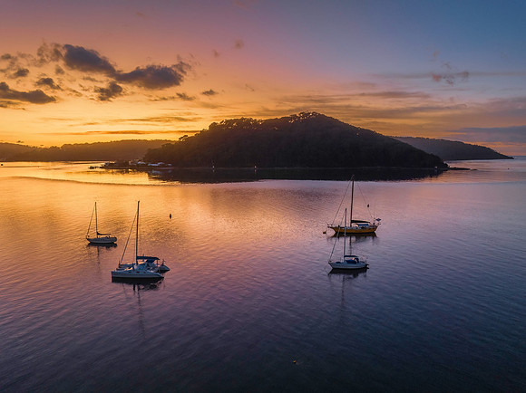 Aerial sunrise waterscape with boats and scattered clouds