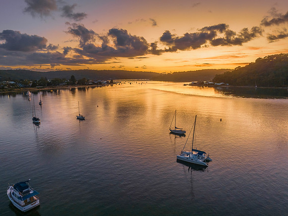 Aerial sunrise waterscape with boats and scattered clouds