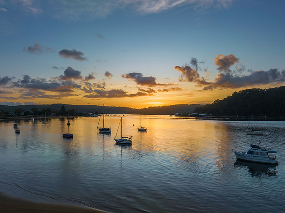 Aerial sunrise waterscape with boats and scattered clouds