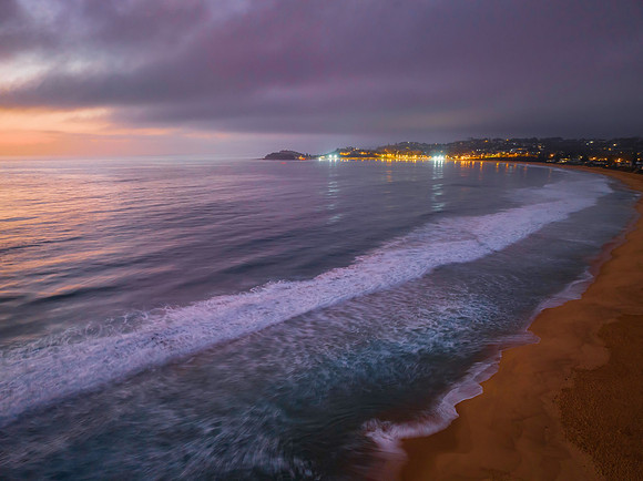 Summer sunrise at the seaside with clouds, haze and town lights