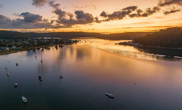 Aerial sunrise waterscape with boats and scattered clouds