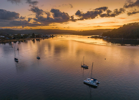 Aerial sunrise waterscape with boats and scattered clouds
