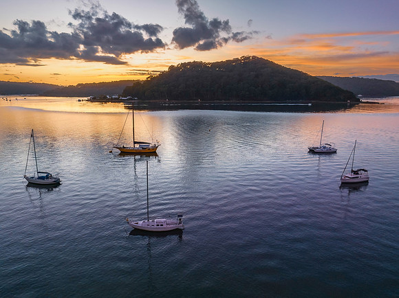 Aerial sunrise waterscape with boats and scattered clouds