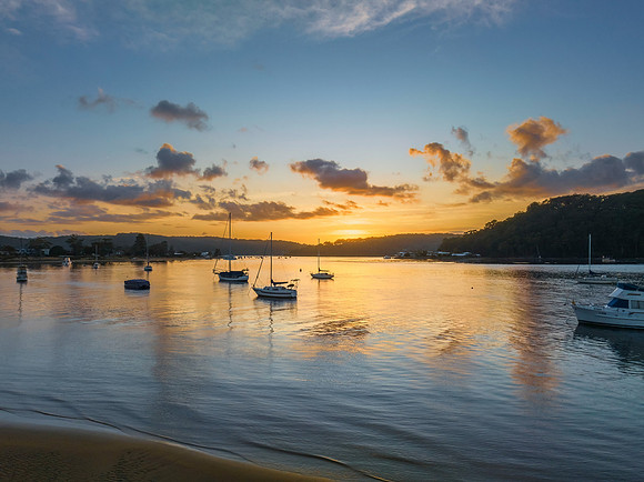 Aerial sunrise waterscape with boats and scattered clouds