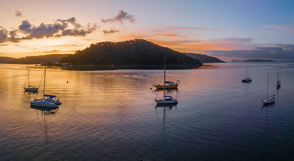 Aerial sunrise waterscape with boats and scattered clouds