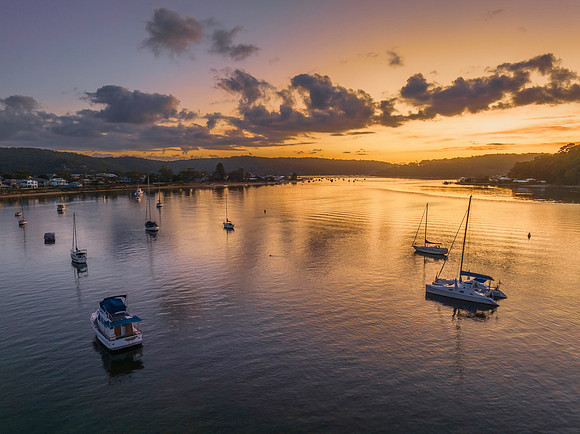 Aerial sunrise waterscape with boats and scattered clouds
