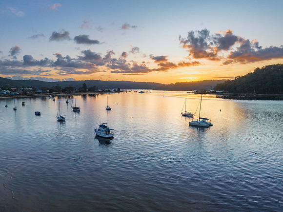 Aerial sunrise waterscape with boats and scattered clouds