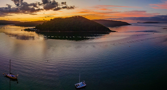 Aerial sunrise waterscape with boats and scattered clouds