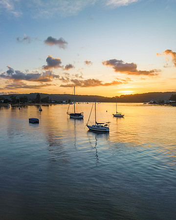 Aerial sunrise waterscape with boats and scattered clouds
