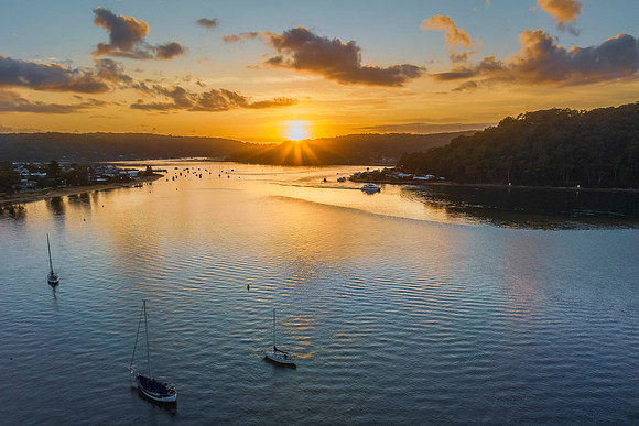 Aerial sunrise waterscape with boats and scattered clouds