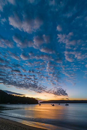 Sunrise views over Brisk Bay with boats, clouds and mountain ran