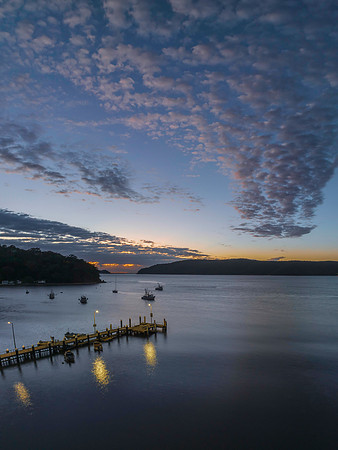 Dawn, clouds and boats on the bay with wharf