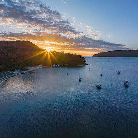 Sunburst over the mountain and boats on the bay