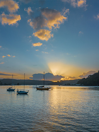 Sunrise over the water with clouds and boats