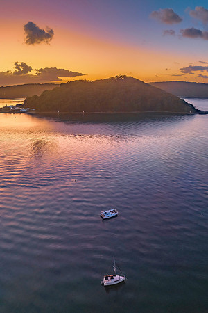 Sunrise over the water with clouds and boats