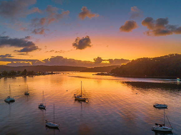 Sunrise over the water with clouds and boats