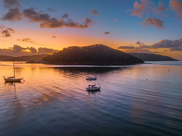 Sunrise over the water with clouds and boats
