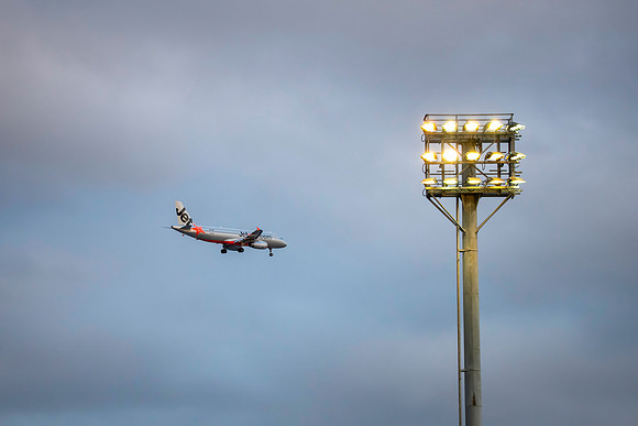 Jetstar Airliner in the early evening sky flying past sports gro