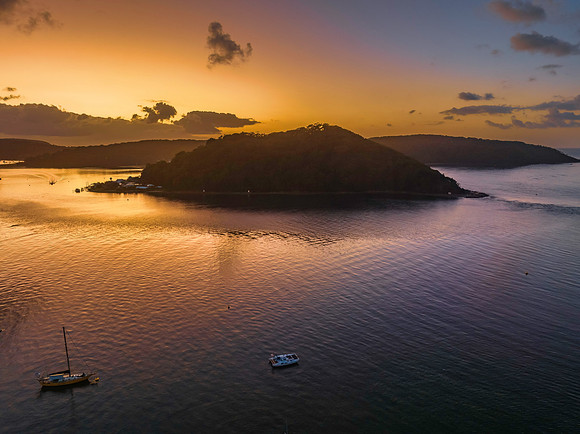 Sunrise over the water with clouds and boats