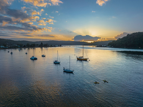 Sunrise over the water with clouds and boats