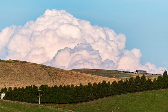Towering Cumulonimbus Clouds Above the Rolling Hills