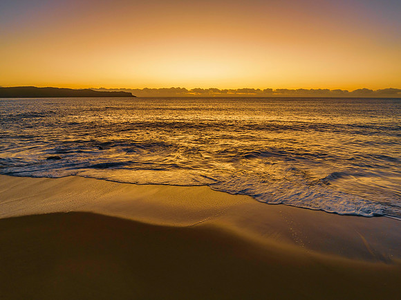 Aerial sunrise seascape with clear skies and low cloud bank