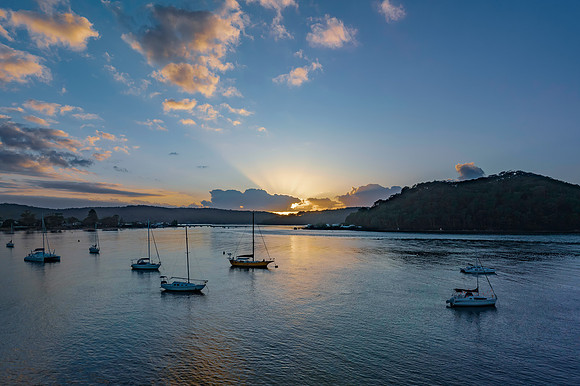 Sunrise over the water with clouds and boats
