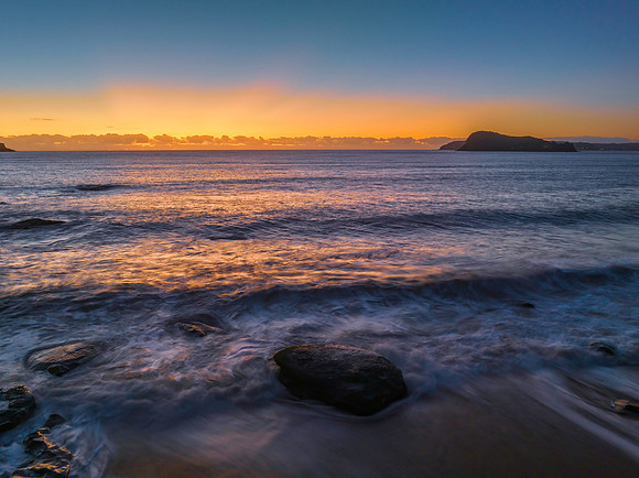 Aerial sunrise seascape with clear skies and low cloud bank