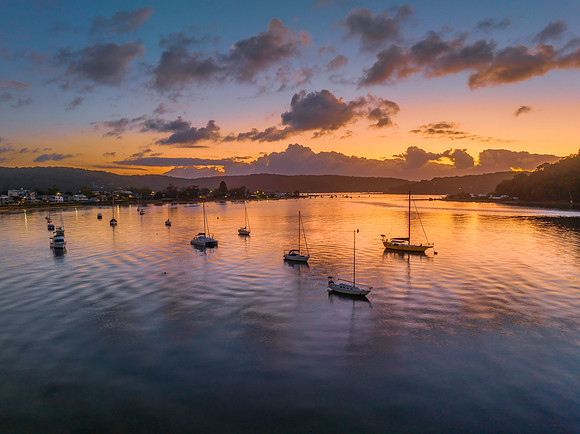 Sunrise over the water with clouds and boats