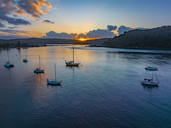 Sunrise over the water with clouds and boats