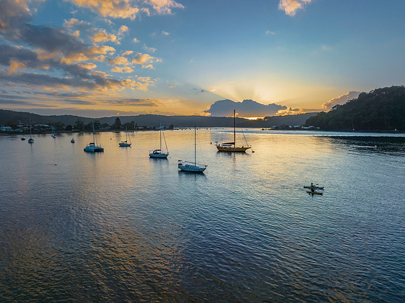 Sunrise over the water with clouds and boats