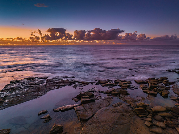 Summer sunrise at the seaside with clouds and rocks