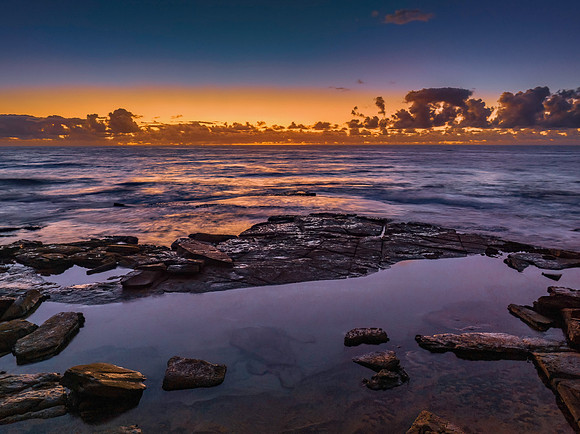 Summer sunrise at the seaside with clouds and rocks