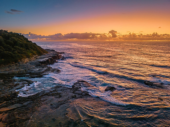 Summer sunrise at the seaside with clouds and rocks