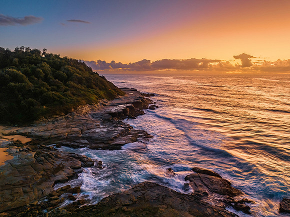 Summer sunrise at the seaside with clouds and rocks