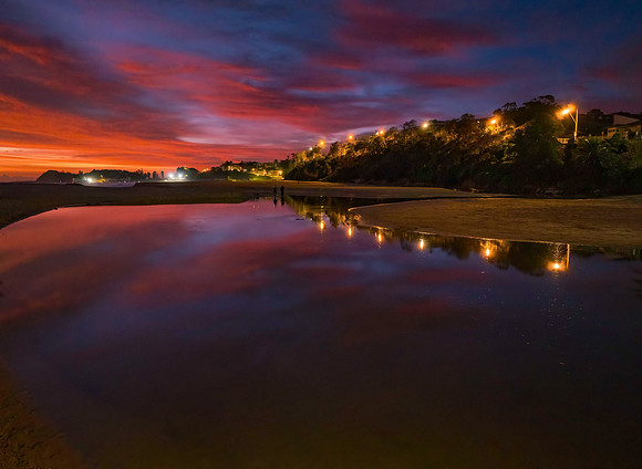 High cloud sunrise at the seaside with street lights and reflect