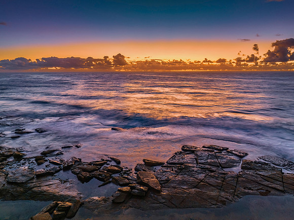 Summer sunrise at the seaside with clouds and rocks