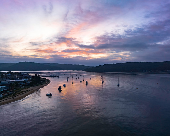 A subtle sunrise waterscape with boats and clouds