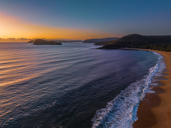 Aerial sunrise seascape with clear skies and low cloud bank