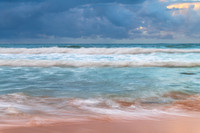 Sunrise at the seaside with rocks and rain clouds