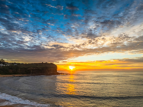 Sunrise Seascape  with Calm Seas and a Cloud Covered Sky