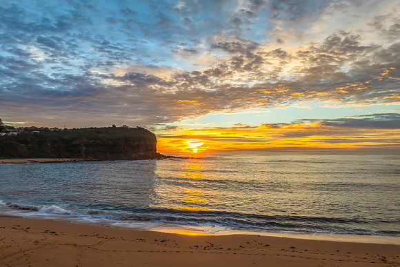 Sunrise Seascape  with Calm Seas and a Cloud Covered Sky