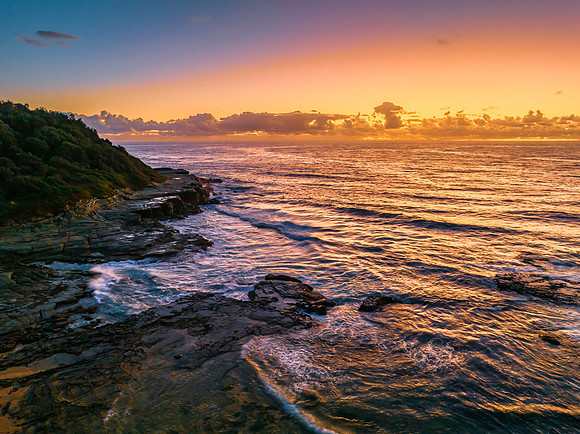 Summer sunrise at the seaside with clouds and rocks