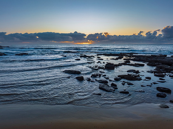 Summer sunrise at the seaside with clouds and rocks
