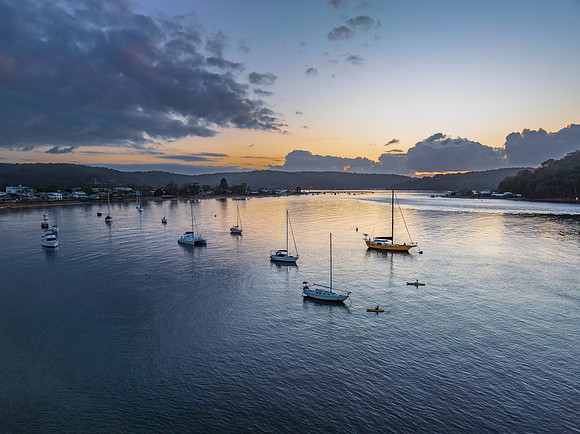 Sunrise over the water with clouds and boats