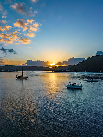 Sunrise over the water with clouds and boats