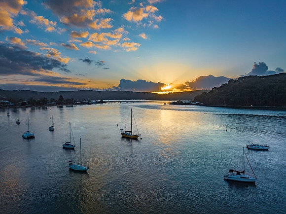 Sunrise over the water with clouds and boats