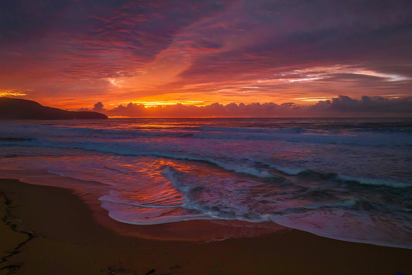 Cloud covered sunrise at the seaside in pink and blue