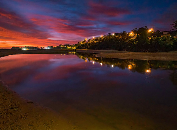 High cloud sunrise at the seaside with street lights and reflect