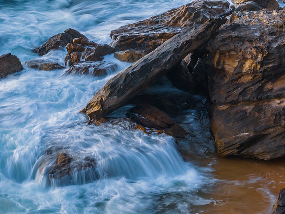 Top down sunrise at the seaside with rocks, waves and swirls